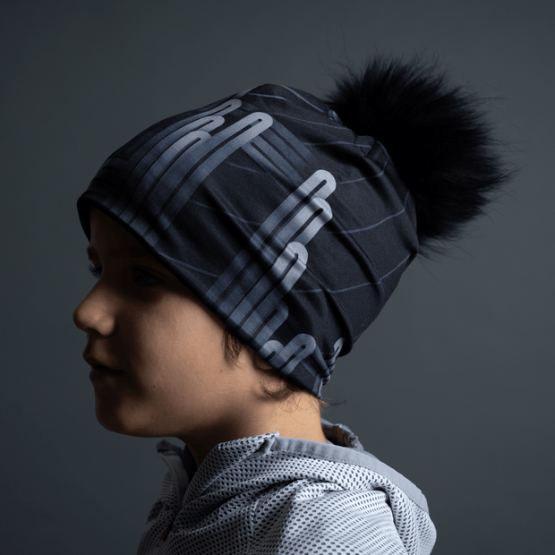 Young boy for the whole family wearing the Radio City black bamboo beanie with detachable pom-pom designed by artist Zaire. Sports hat for men and boys, perfect for soccer, jogging, skiing, skating and hiking. All season hat