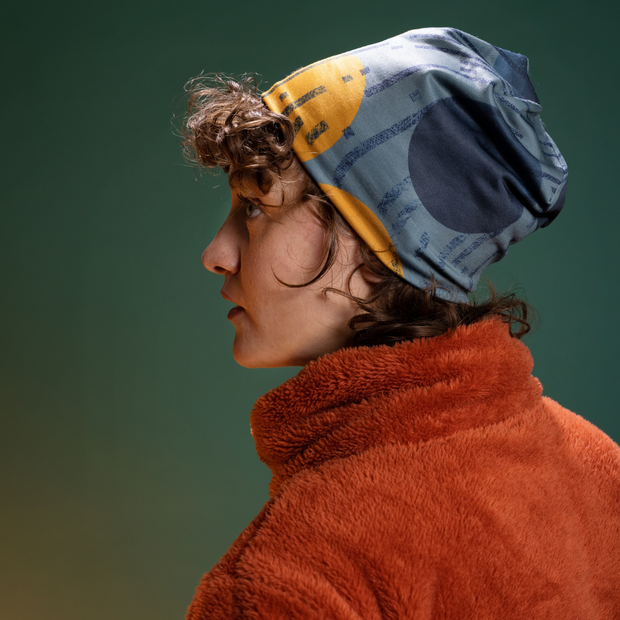 Young Woman beautifully wearing the Lalita's Art Shop Beanie Movement Orange with short curly hair paired with an dark orange fleece shirt. 