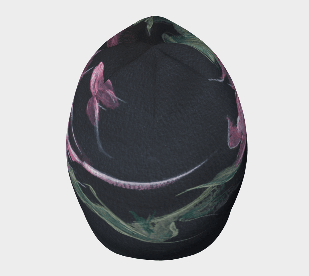 A black beanie with a pink and green floral art print shown from the top with a curved design.