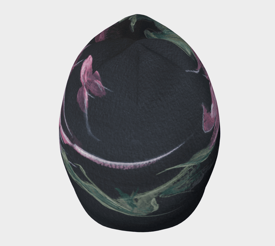 A black beanie with a pink and green floral art print shown from the top with a curved design.