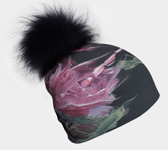 Close-up of a baroque-style beanie with a black fluffy pompom and a pink floral painting.