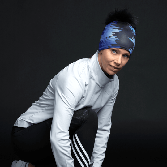 Femme portant la tuque "Black War" avec pompon noir et motif abstrait bleu, en tenue sportive.