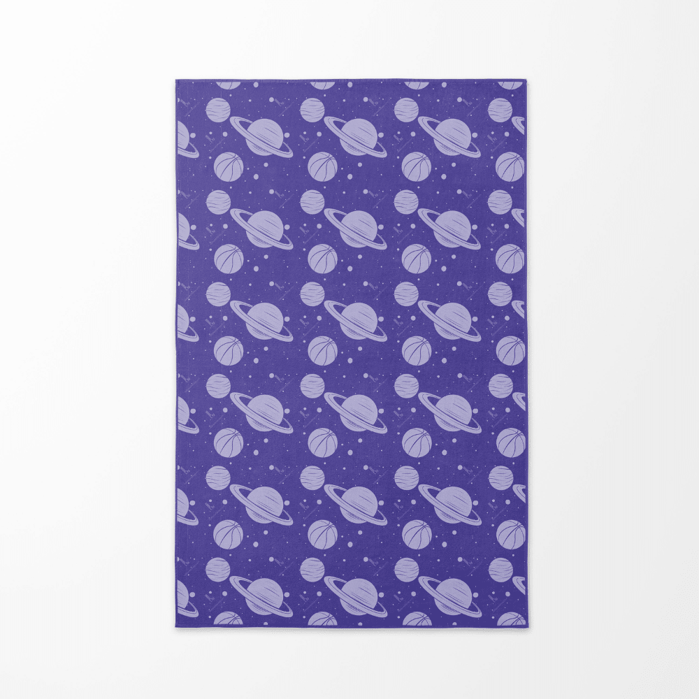 Face arrière de la serviette de plage "Cosmic Slam" avec un motif répétitif de planètes violettes et de ballons de basketball sur un fond étoilé.