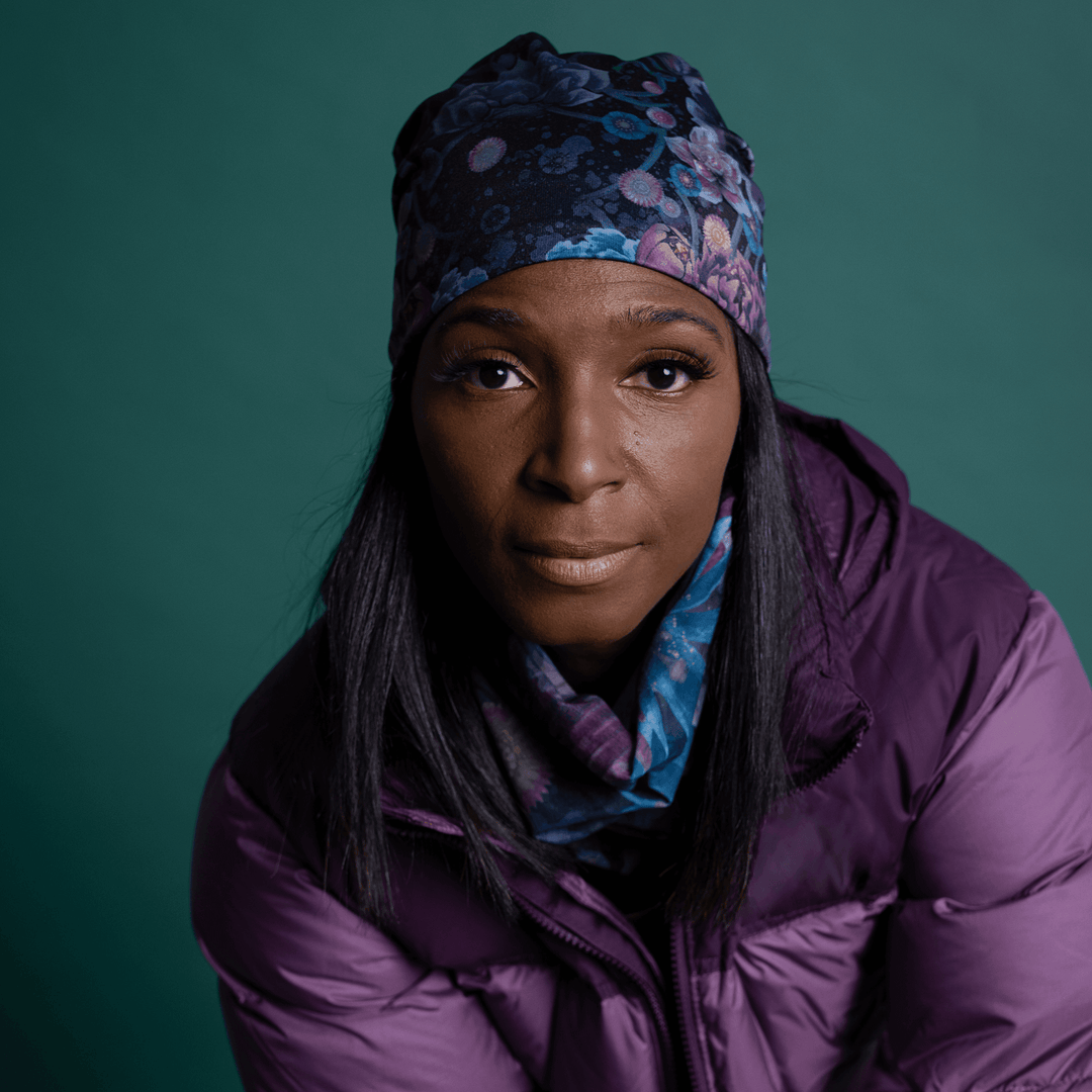 Woman indoors wearing the floral beanie, which matches a patterned scarf around her neck.