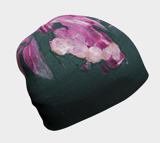 A relaxed fit beanie with a dark green base and a vibrant pink, white, and gold abstract floral print.