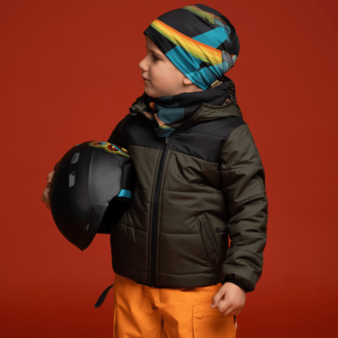Jeune garçon portant la tuque Soucoupes Volantes et un cache-cou assorti, tenant un casque.