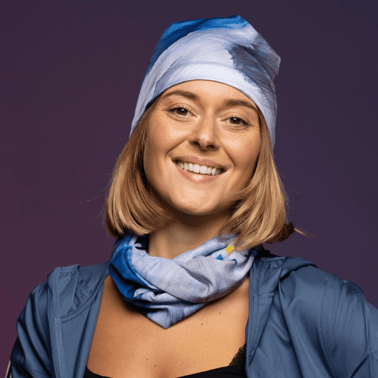 Woman smiling, wearing the Golden Sea Beanie and matching neck tube with a blue jacket.
