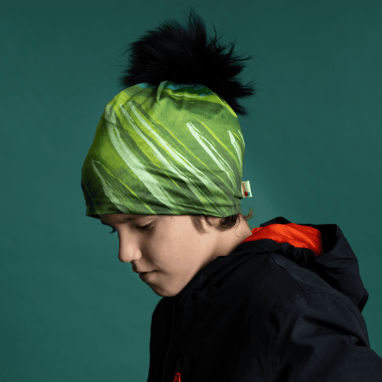 Un jeune garçon portant la tuque fine "Green Light" avec un pompon noir, regardant sur le côté.