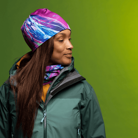Une femme portant une veste verte, un chandail jaune et le tube Espoir en tuque et cache-cou.