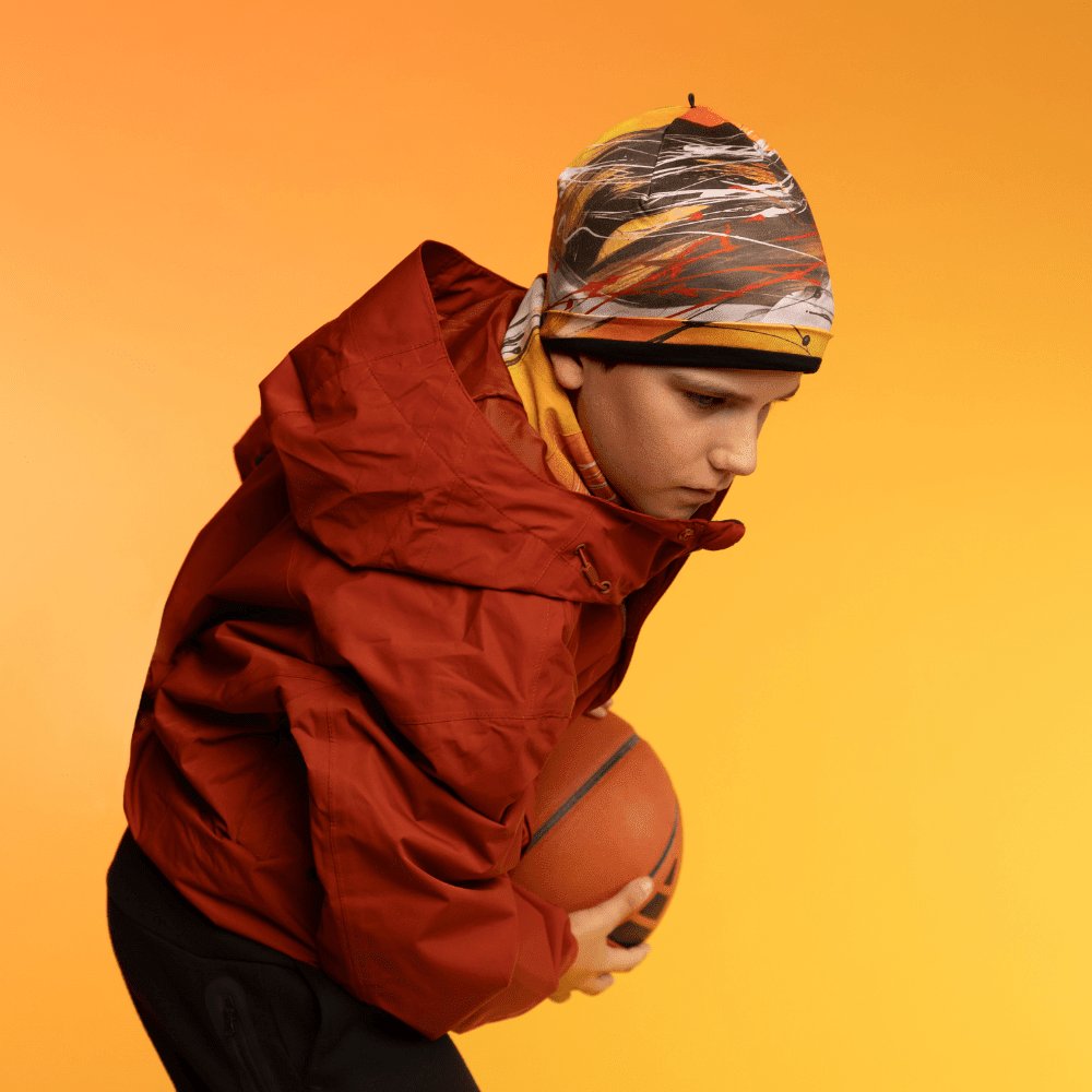 Young person wearing the Le Coeur Beanie and a red jacket, holding a basketball.