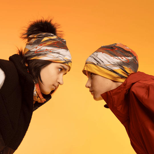 Profile view of two young people wearing the Le Coeur Beanie and neck gaiters.