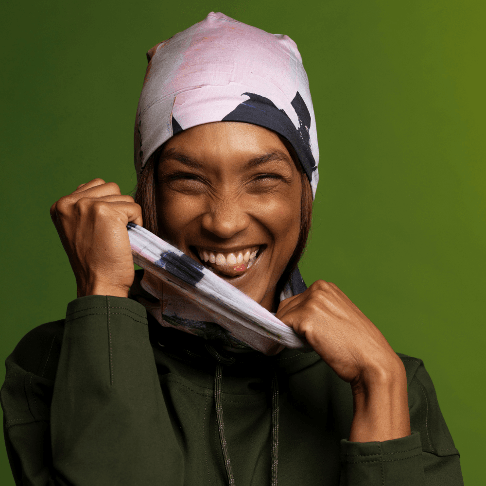 Gros plan sur une femme souriante retirant le tube multifonctionnel « Modern Quilt » de son visage, montrant le motif d&
