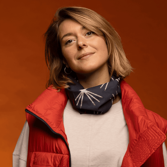 Femme portant un gilet rouge et un haut blanc, avec un tube multifonctionnel bleu marine à motifs d&
