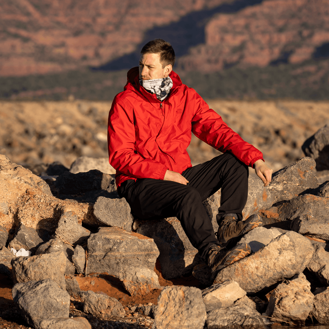 Homme en veste rouge assis sur des rochers à l&