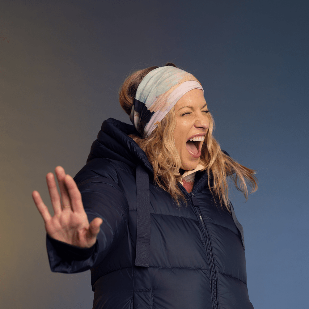 A woman wearing a navy puffer jacket and a headscarf made from the &