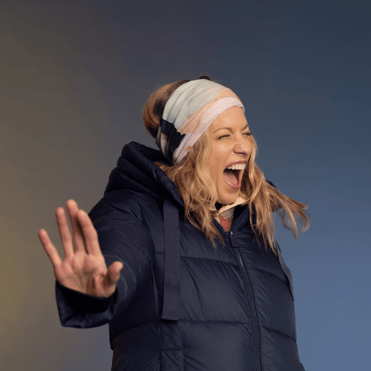 A woman wearing a navy puffer jacket and a headscarf made from the &