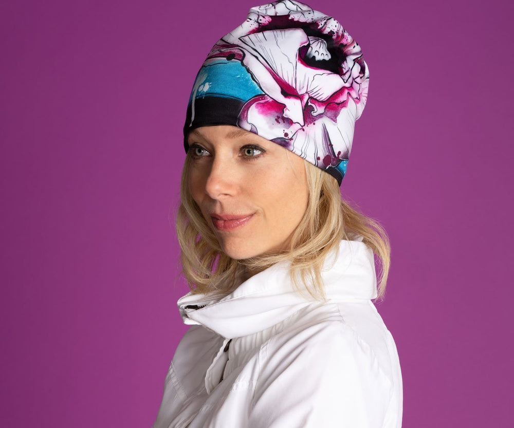 Femme portant la nouvelle tuque Pavot, qui présente un design floral coloré et un pompon noir.