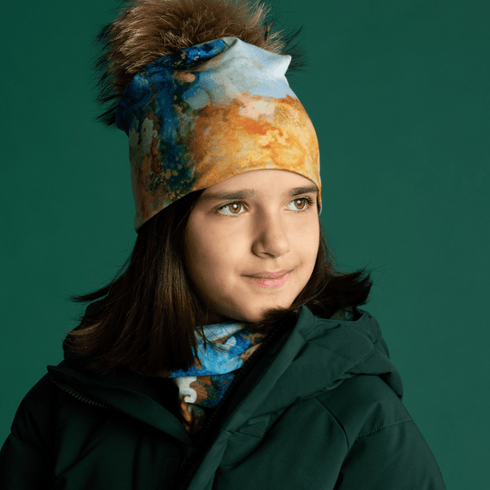 Une jeune fille portant la tuque et la tuque "Marbre Océan" regarde sur le côté, mettant en valeur l&