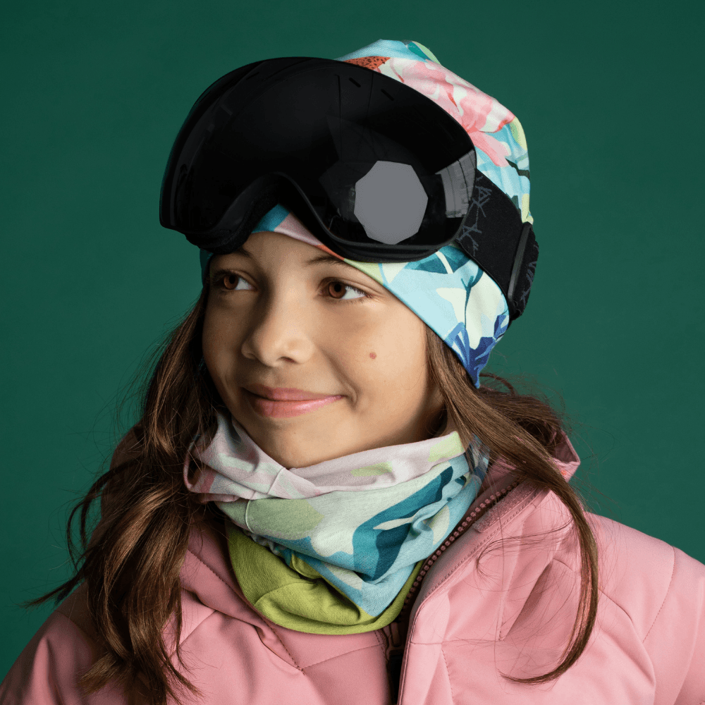 Jeune fille portant la tuque Fleurs Pastel et un cache-cou assorti avec des lunettes de ski.