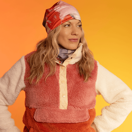 Woman wearing a beanie with abstract art and a multi-coloured neck gaiter.