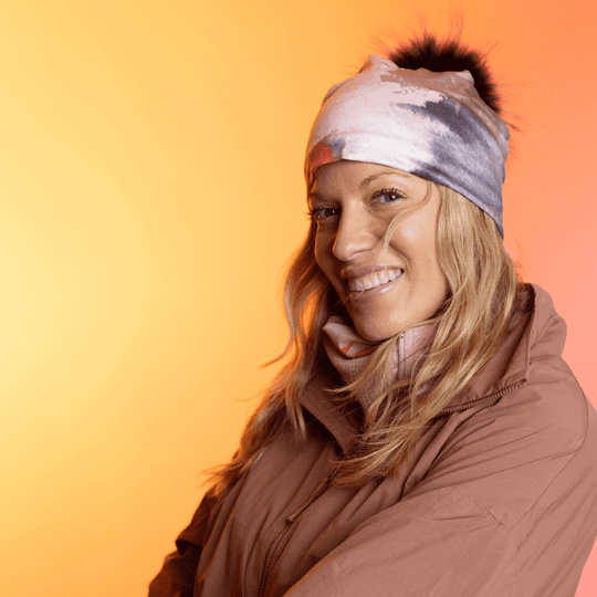 Femme souriante portant la tuque Rose et Flammes avec un pompon noir.