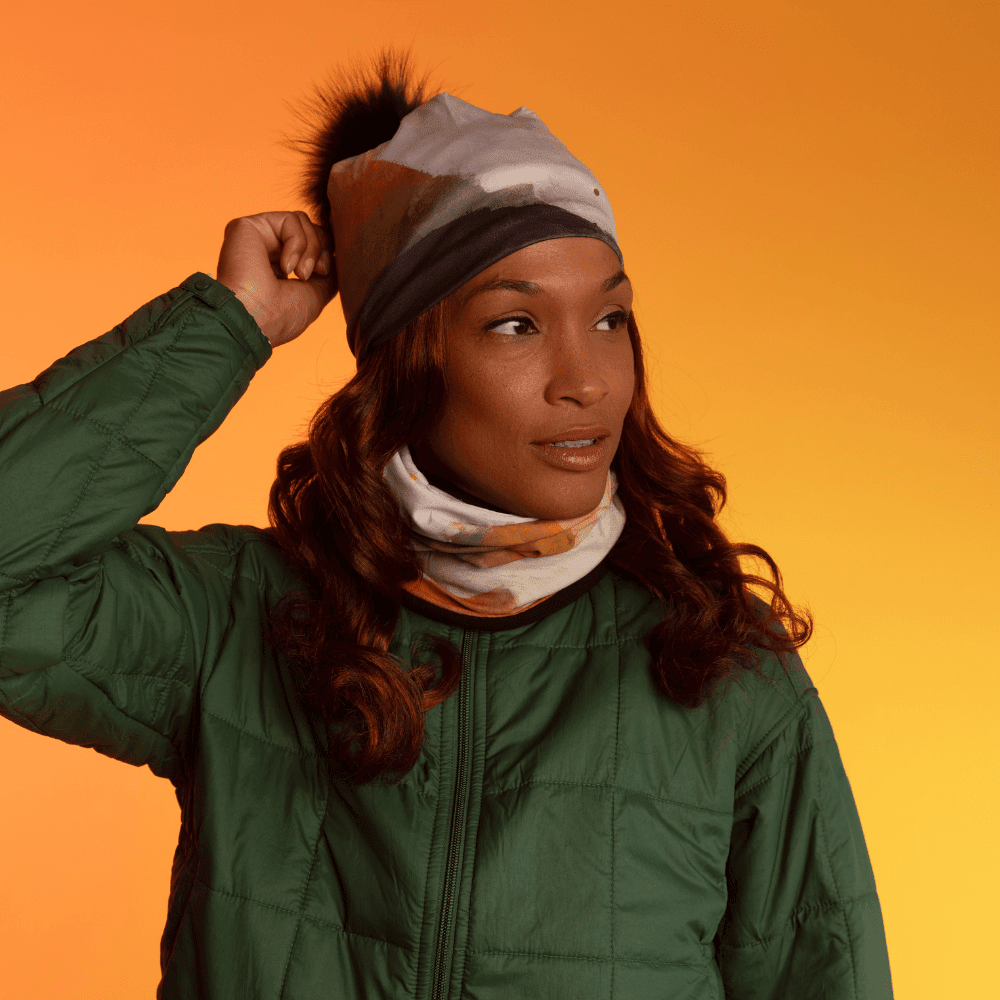 Une femme portant une veste matelassée verte, avec le tube multifonction POLAR Accent Marine stylisé en cache-cou, dépassant de son col.