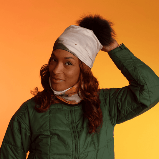 Une femme portant une veste matelassée verte, ajustant une tuque ornée d&