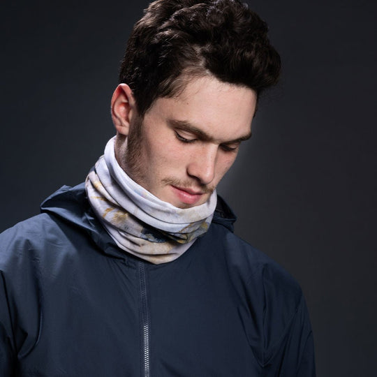 Homme portant une veste marine, avec le cache-cou à imprimé abstrait autour du cou.