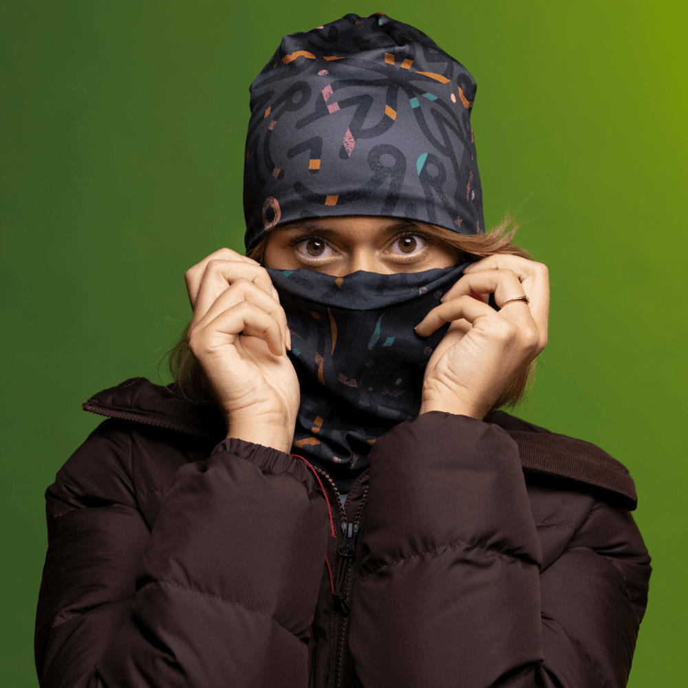 Une femme portant une veste d'hiver foncée remonte le tube multifonction POLAR Symetrick Gray sur son nez, révélant son motif artistique.
