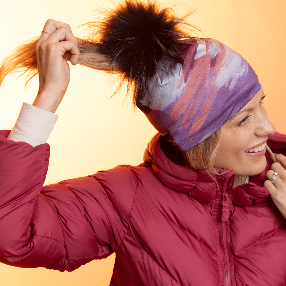 Femme portant la tuque Ponytail Tulips avec pompon noir, une veste rouge et une queue de cheval.
