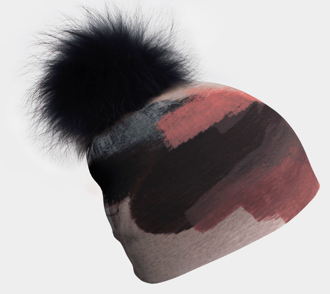 Tuque avec pompon noir et motif abstrait de coups de pinceau en corail, gris et noir.