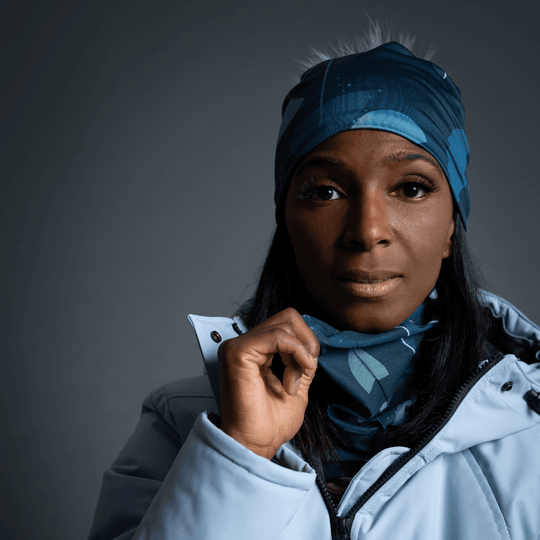 Close-up portrait of a woman wearing a light blue winter jacket and the teal beanie and neck warmer.