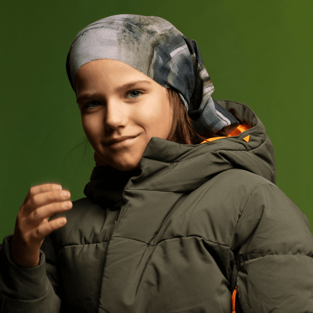 Jeune fille portant le Tube Multifonction Murale en bandeau avec une veste matelassée verte.