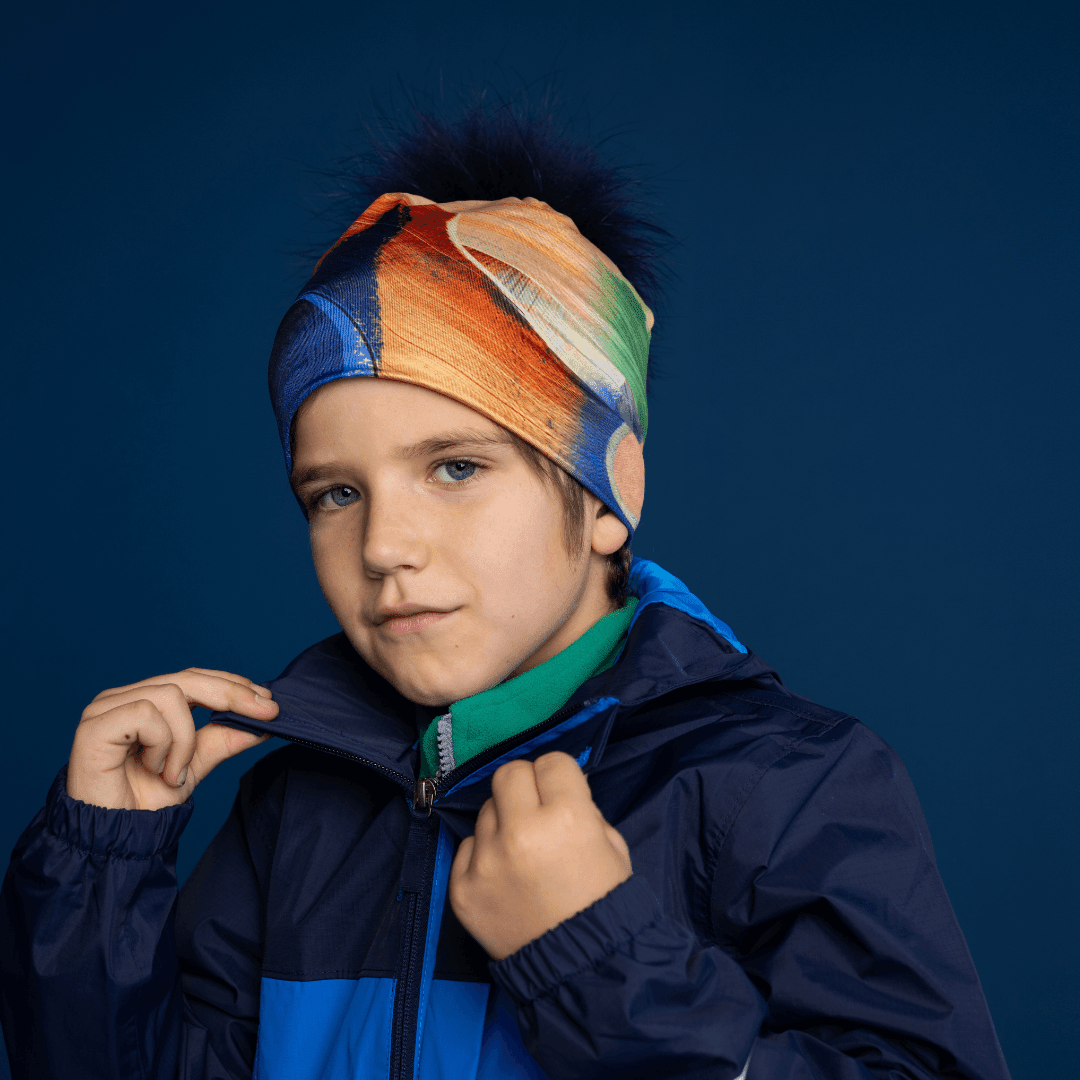 Young boy wearing the Yellow &amp; Blue Beanie with removable navy fur pom, styled with a jacket.