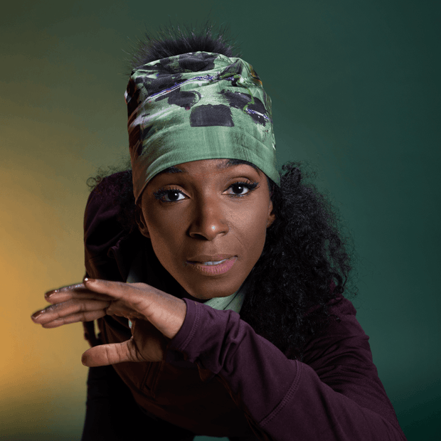 Beautiful woman wearing the green and black abstract Amazonia Beanie Hat with revable fur pom illustrated by painter Megane Fortin 