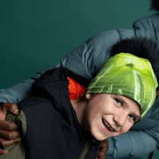 Boy smiling wearing the Green Light beanie with black pompon by Andre Martel for the Lalita's Art Shop 22 collection.