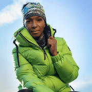 Black woman from the front wearing a green winter coat and the Meduse hat designed by Mégane Fortin. This beanie is a beanie with an abstract design and a detachable pom pom
