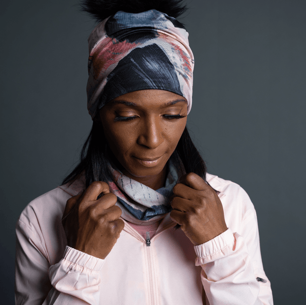 Woman in front looking down, wearing the multifunctional tube La vie en Rosel illustrated by Catherine Parent. This beautiful bandana can be worn in more than 10 different ways! Unisex, this scarf is perfect to the whole family and is perfect for outdoor activities !  She also wears the matching hat.