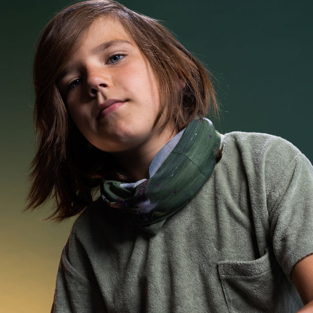 Boy wearing the green abstract multi-use necktube by Lalita's art Shop and illustrated by Megane Fortin
