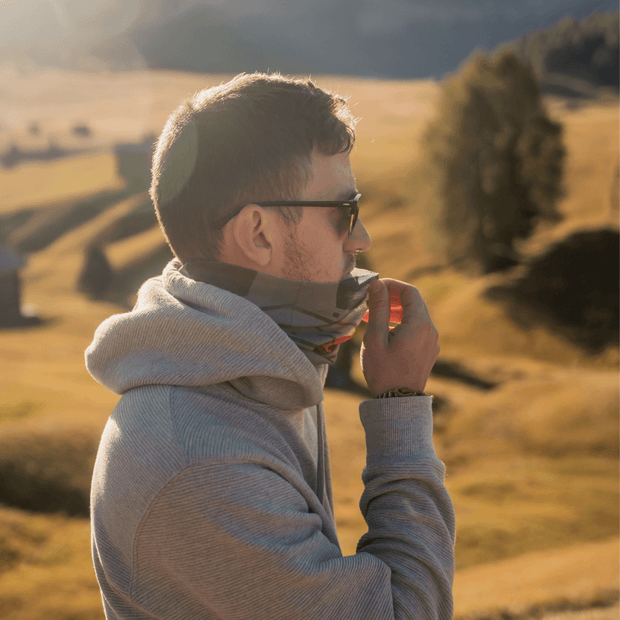 Young men outside with sunset wearing the Lalita's art Shop Multipurpose tube Movement Orange as a neck warmer