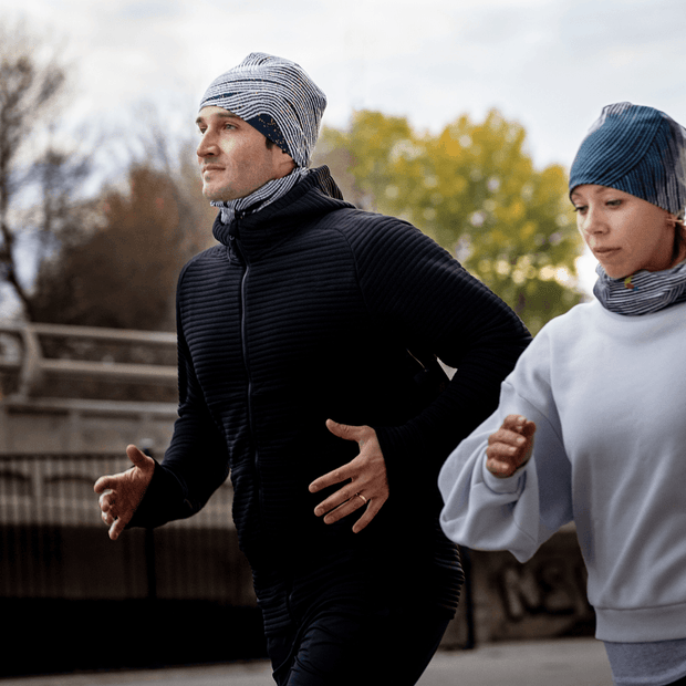 this ligtweith and brethable toque is the best hat for running. man and woman running with the new collection by Valery Goulet. A dark grey steel color beanie with an abstract white and orange pattern.