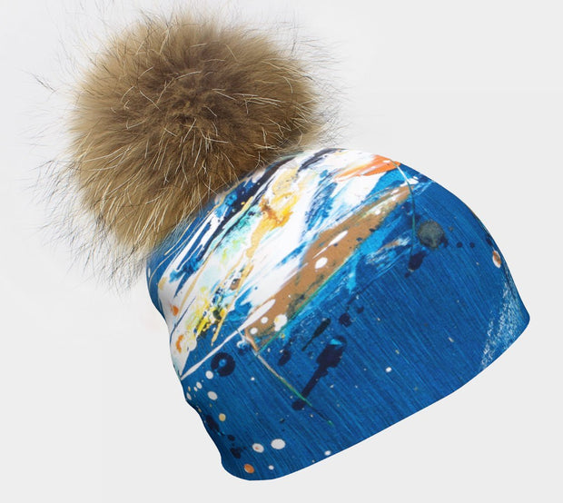 Left side view of the Beanie hat for children and adults Bleu-Terre by the talented Youg Artist Megane Fortin. The magnificent big natural fur Pompom is removable. 