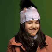 Laughing teenager wearing the Blush and Black Modern Quilt Beanie with Black Pompom by Catherine Parent for the Lalita's Art Shop 24 collection