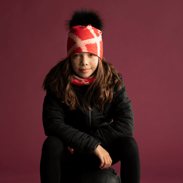 Teenage gril wearing the vibrant red beanie with peach lines. You can also see the  multifunction tube to match with it 