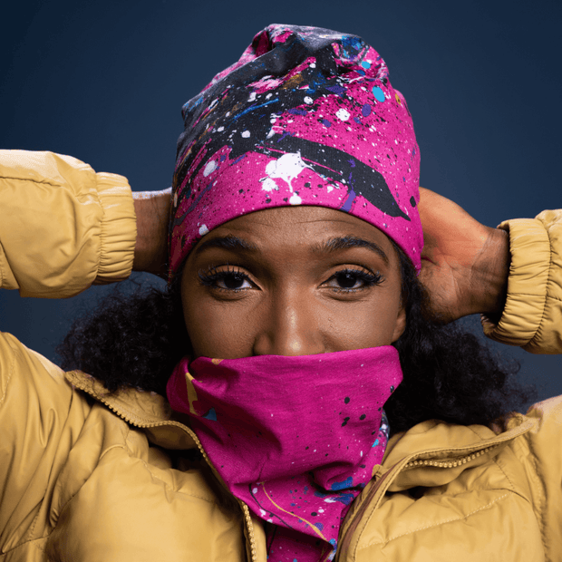 Woman wearing the duo Nest BEanie hat and Multi-Use neck tube with fleece  Nest with a yellow - gold jacket. 