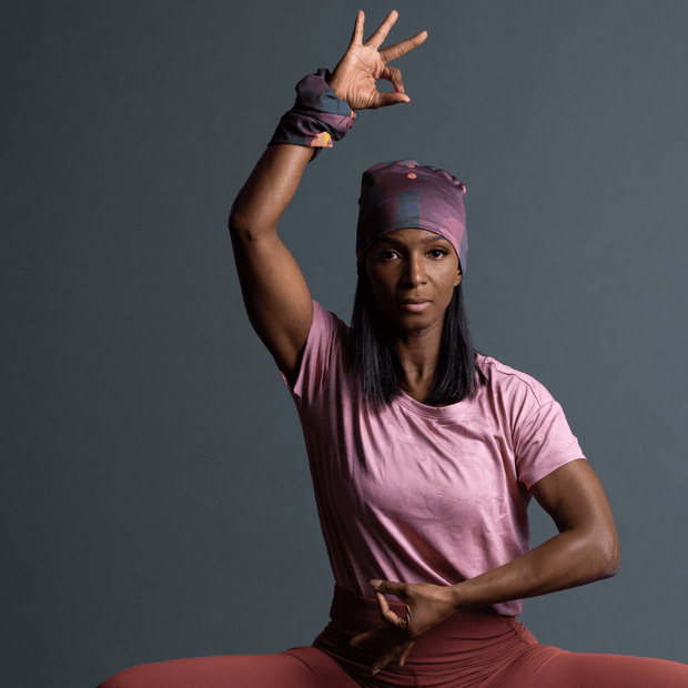 Woman with her arm raised wearing a mid-season beanie designed by Zaire. This bamboo hat in shades of purple is perfect for outdoor activities and yoga.
