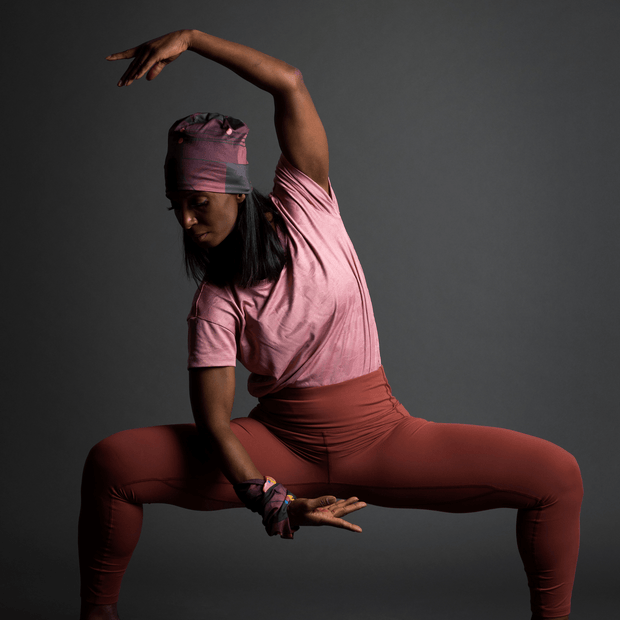Sportswoman doing yoga stretches. She is wearing the purple Geometrics bamboo sports cap designed by Valéry Goulet an amazing artist from Quebec. This sports cap is perfect for indoor and outdoor sports activities and fits all body types.