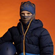 Young skier wearing the Navy and Orange Sunrise Bamboo Beanie and multifunctional tube for Lalita's Art Shop