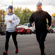 Couple running at night in the city with their Lalita's Art Shop beanies and tubes. 