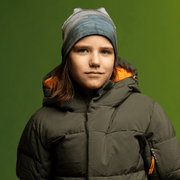 Boy smiling at the camera in his winter coat wearing the Green and Gray Wall Beanie from Lalita's Art Shop